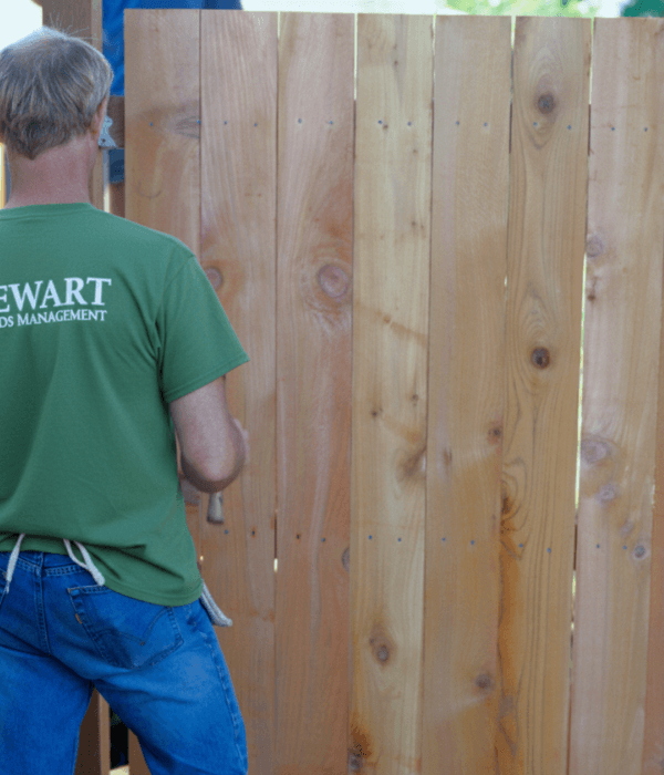 Stewart Grounds Management team member installing a wooden privacy fence in Lafayette, LA — professional fence and deck installation services across Acadiana.